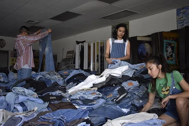 Shoppers digging through piles of vintage Levi's jeans at Drop Your Jeans in Covina